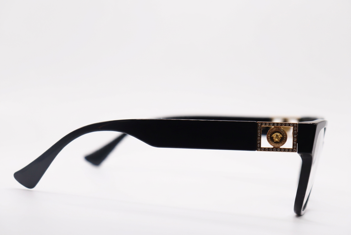 Black eyeglasses with gold temple details, side view on a white background